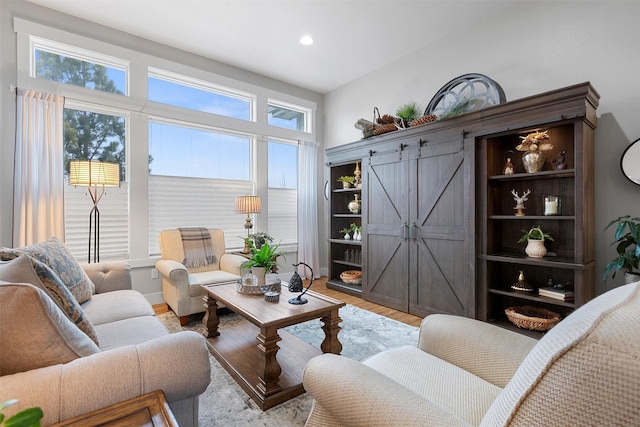 living room with a barn door, light wood-style flooring, and recessed lighting