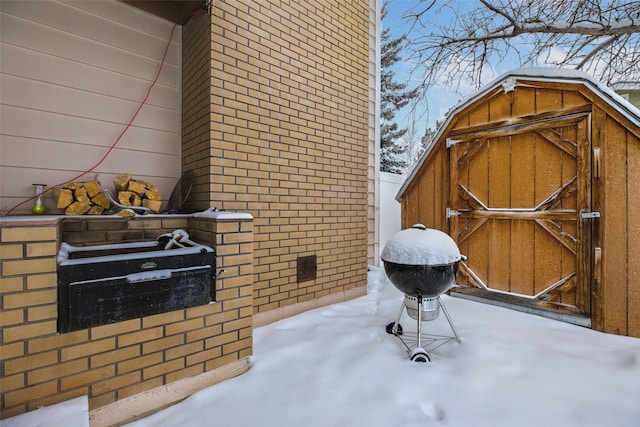 snow covered patio with an outbuilding and a storage unit