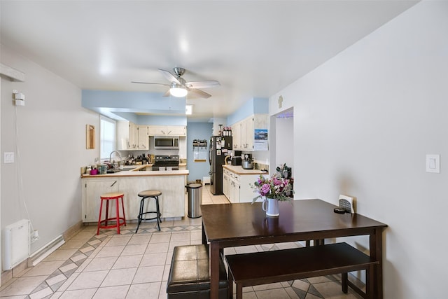 dining room featuring ceiling fan, baseboards, and light tile patterned flooring