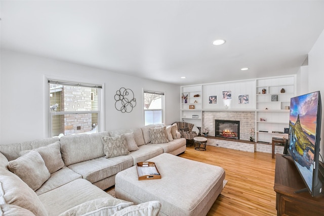 living room with light wood finished floors, a fireplace, built in features, and recessed lighting