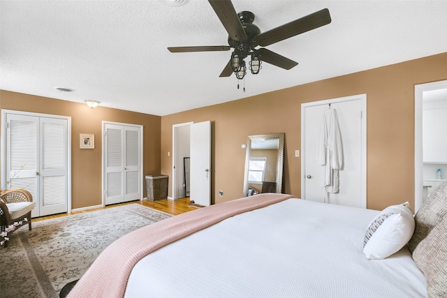 bedroom featuring a textured ceiling, connected bathroom, visible vents, and multiple closets