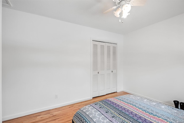 bedroom with ceiling fan, a closet, wood finished floors, and baseboards