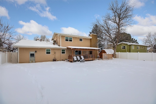 snow covered house featuring fence and a chimney