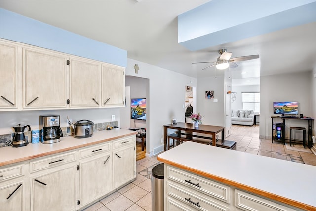 kitchen with light tile patterned floors, baseboards, light countertops, and a ceiling fan