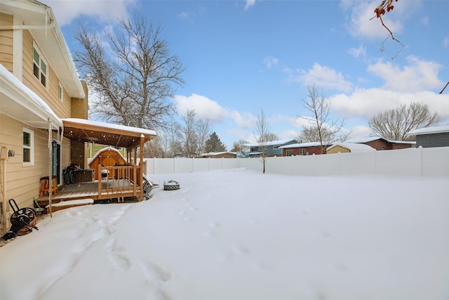 yard covered in snow with fence and a deck