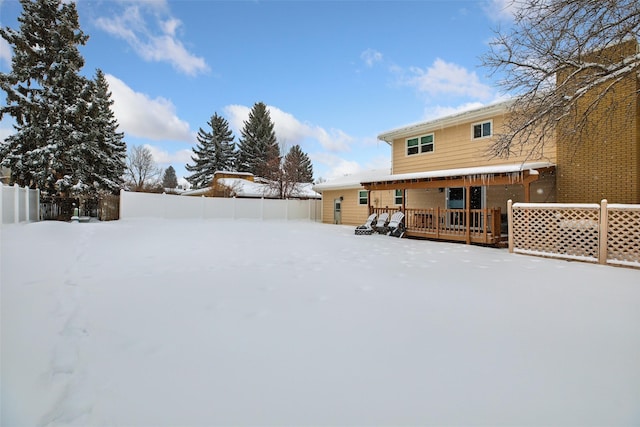 yard covered in snow featuring fence and a wooden deck