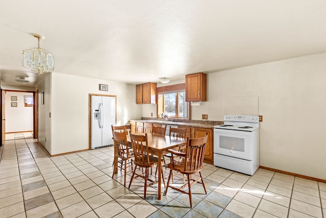 kitchen featuring decorative light fixtures, light tile patterned floors, brown cabinetry, a sink, and white appliances