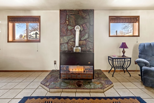 sitting room with a wood stove, baseboards, and light tile patterned floors