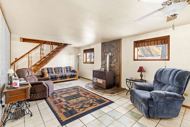 living room featuring light tile patterned floors, a wood stove, and a ceiling fan