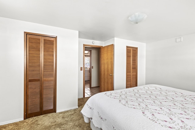 bedroom featuring baseboards, multiple closets, and carpet flooring