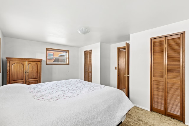 carpeted bedroom featuring baseboards and two closets