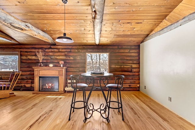 dining room with wooden ceiling, a glass covered fireplace, rustic walls, and light wood-style floors