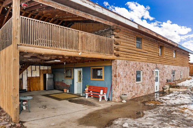 back of house with log exterior and a balcony