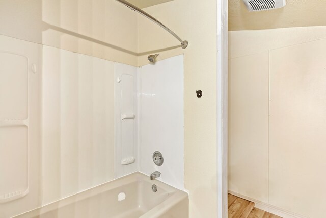 bathroom with bathtub / shower combination, visible vents, and wood finished floors