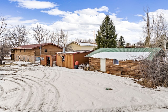 snow covered rear of property featuring metal roof