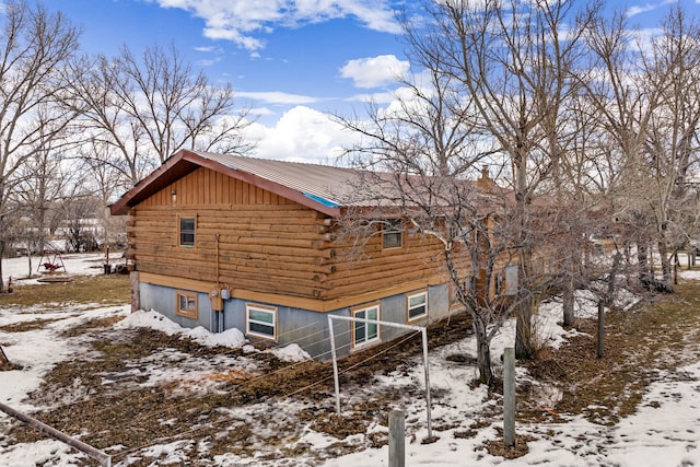 view of snowy exterior with log siding