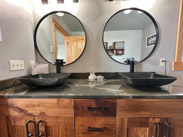 bathroom featuring double vanity, a sink, and a textured wall