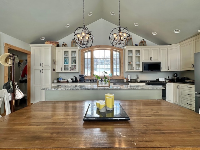 kitchen with glass insert cabinets, vaulted ceiling, appliances with stainless steel finishes, and pendant lighting