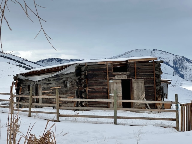 view of front facade with an outbuilding, an exterior structure, a mountain view, and log siding