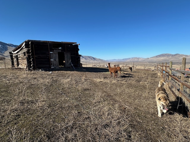 view of yard with an outbuilding, a rural view, a mountain view, and fence