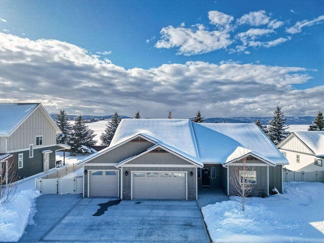 view of front of property featuring driveway, board and batten siding, an attached garage, and fence