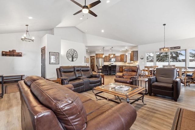 living area with ceiling fan with notable chandelier, high vaulted ceiling, light wood finished floors, and recessed lighting