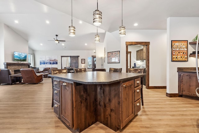 kitchen with open floor plan, dark countertops, a kitchen island, and decorative light fixtures