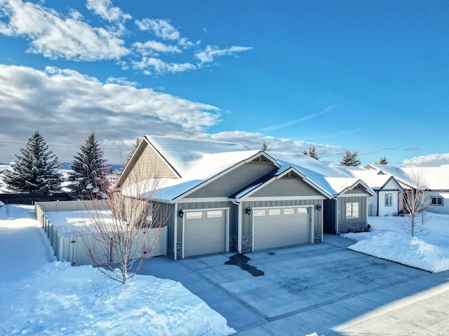 ranch-style house with an attached garage, board and batten siding, fence, stone siding, and driveway