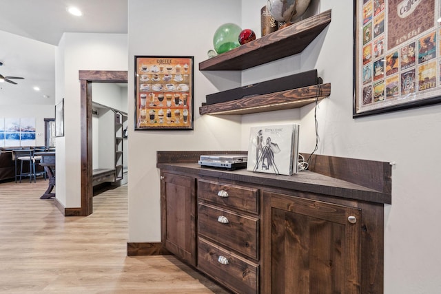 bar featuring light wood-style floors, ceiling fan, and baseboards