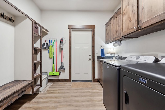 washroom featuring cabinet space, baseboards, light wood-type flooring, separate washer and dryer, and a sink