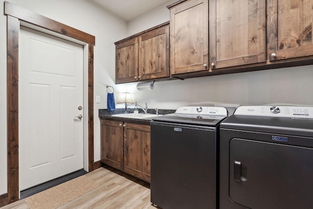 washroom with light wood-type flooring, cabinet space, a sink, and independent washer and dryer