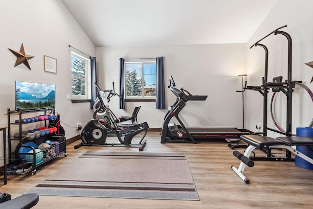 exercise room featuring lofted ceiling and light wood-style flooring