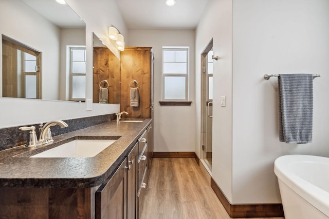 bathroom with a freestanding tub, wood finished floors, a sink, baseboards, and a shower stall