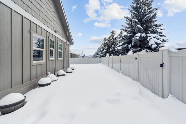 yard layered in snow with a gate and fence