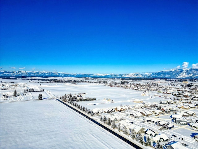 snowy aerial view featuring a residential view and a mountain view