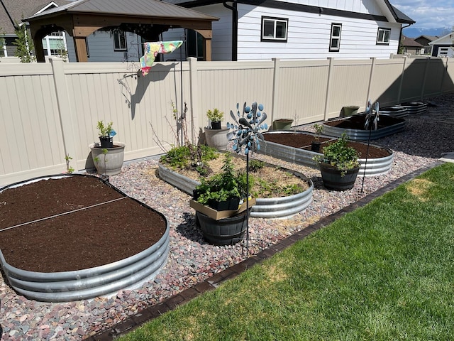 view of yard featuring a gazebo, fence, and a garden