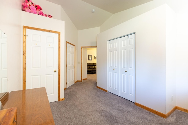 hall featuring lofted ceiling, carpet flooring, and baseboards