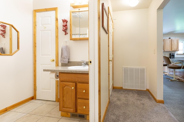 hallway with light tile patterned flooring, a sink, visible vents, and baseboards