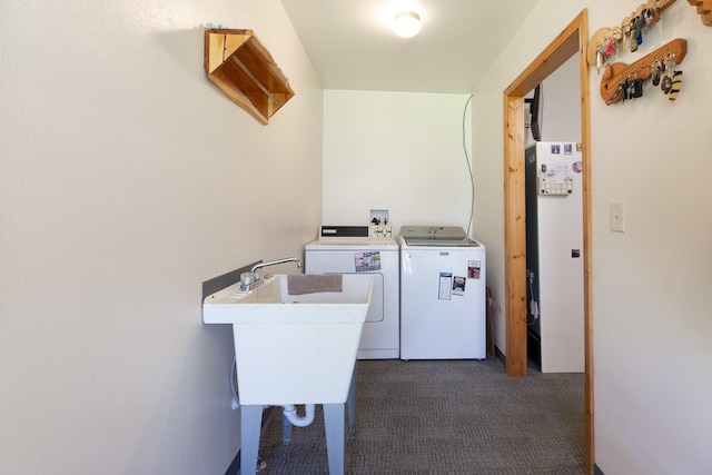 clothes washing area featuring a sink, laundry area, dark colored carpet, and washer and dryer