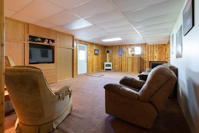 living room featuring plenty of natural light, carpet, a wood stove, and wood walls