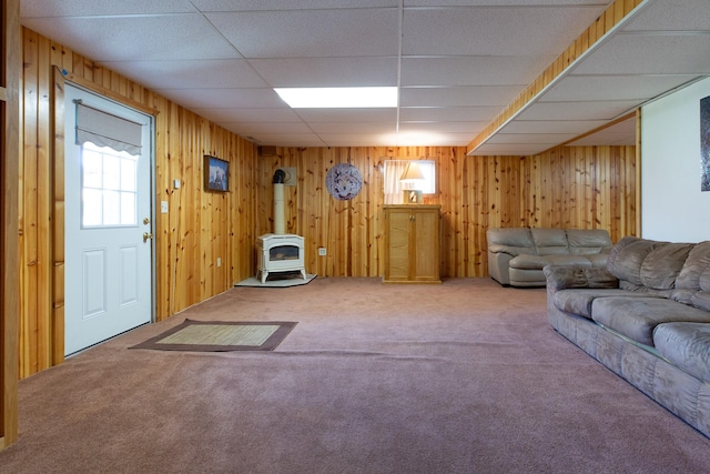 carpeted living area with wood walls and a wood stove