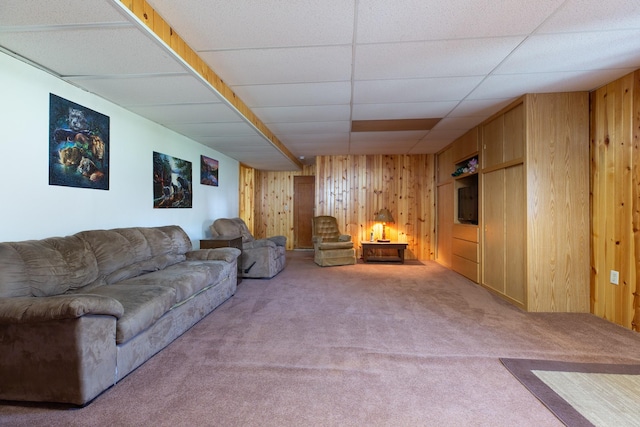 living area with carpet, a drop ceiling, and wood walls