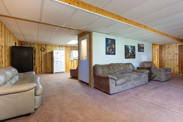 living area featuring carpet, a paneled ceiling, and wooden walls