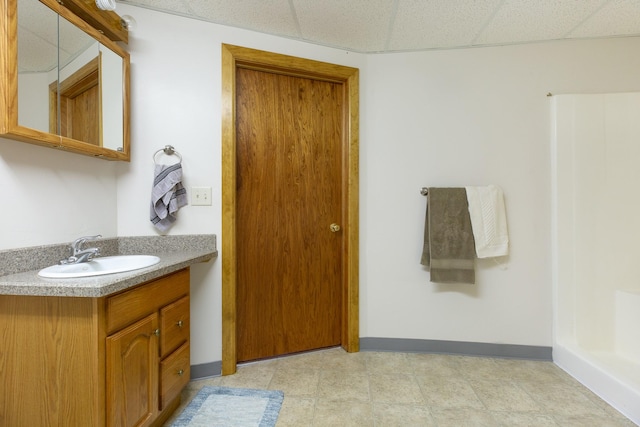 bathroom featuring a paneled ceiling, vanity, and baseboards