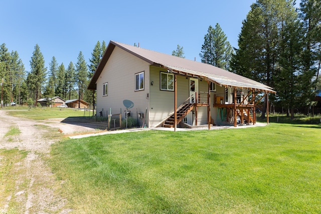 view of front of home with stairs, metal roof, a front lawn, and driveway