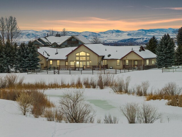 920 Antelope Ridge Rd, Belgrade, MT 59714 - snow covered back of property featuring a mountain view, board and batten siding, and fence