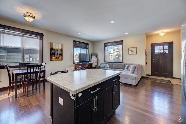 kitchen with dark wood-style floors, a center island, light countertops, open floor plan, and dark cabinetry