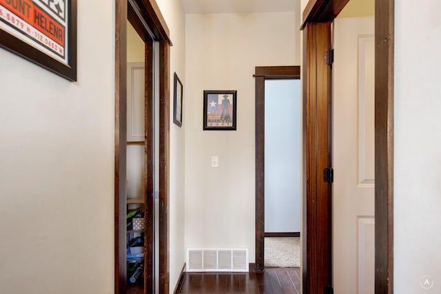 hall with visible vents, dark wood finished floors, and baseboards