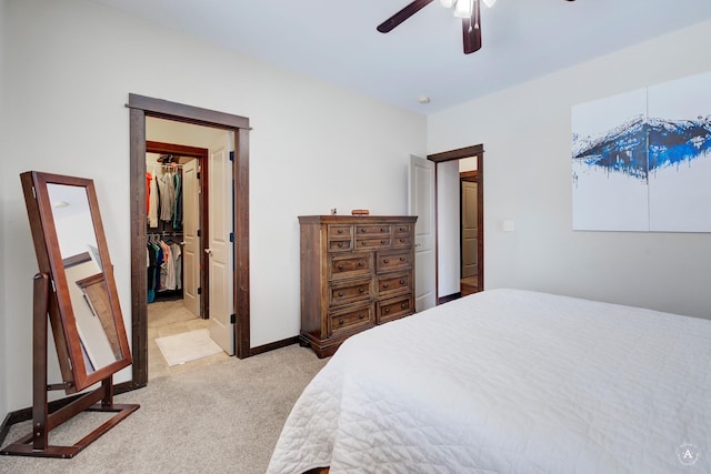 bedroom featuring ceiling fan, light colored carpet, baseboards, a spacious closet, and a closet