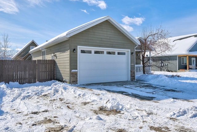 snow covered garage featuring fence